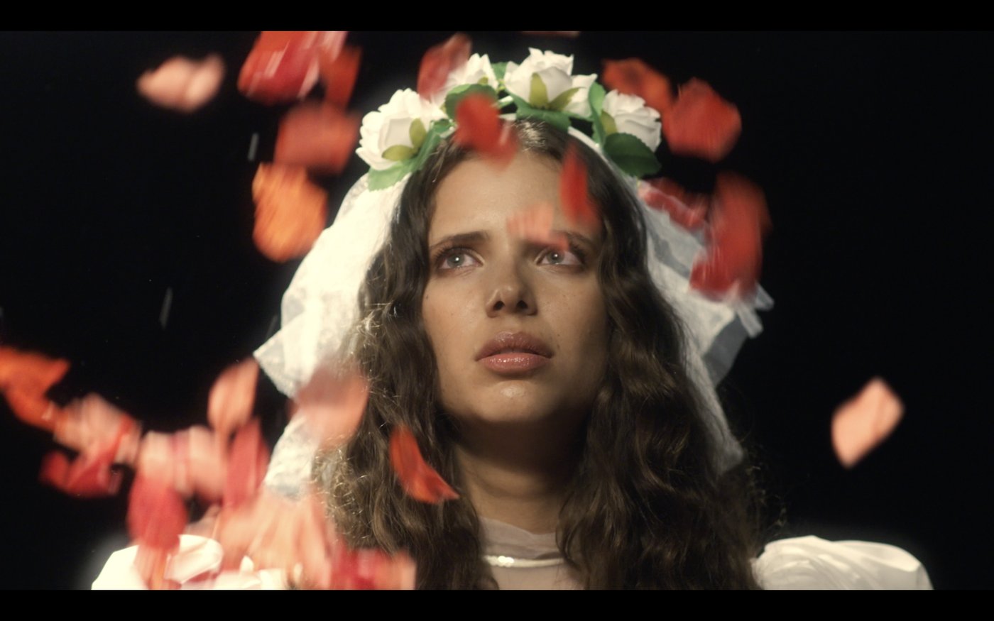 Amsterdam Ave. still: a woman in a flower crown under falling red petals