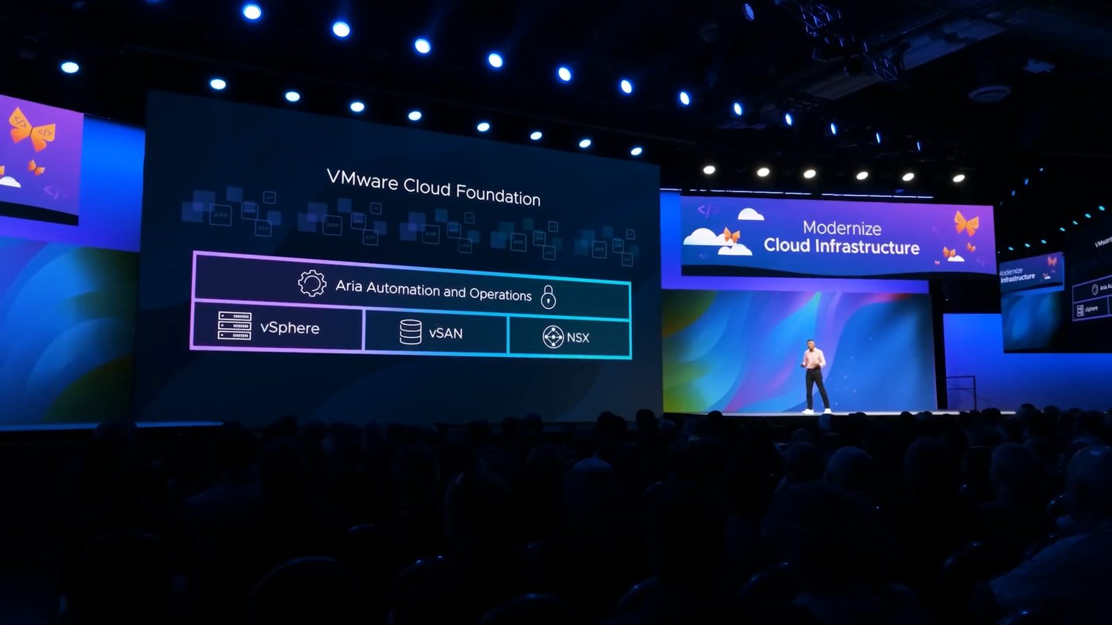 Corporate editing reel still: a presenter on a large conference stage in front of VMware Cloud Foundation slides